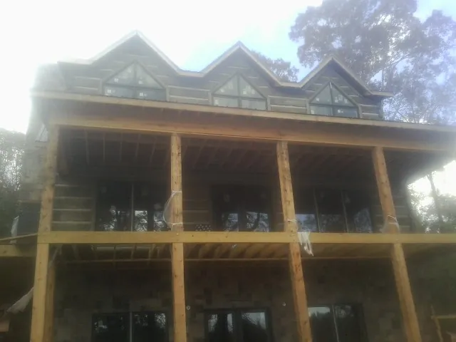 Dormers and porch framing on a large log home under construction — Roof Coating work by our crew in Silver Spring