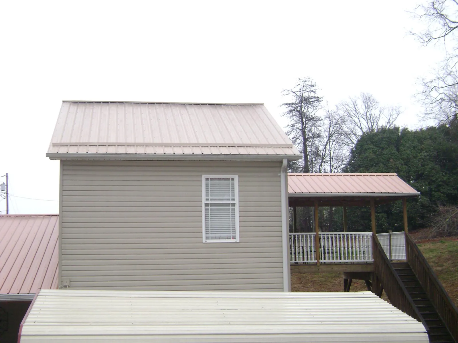 Tan metal roofs on a two story addition and attached porch, from a Roof Replacement job in Silver Spring