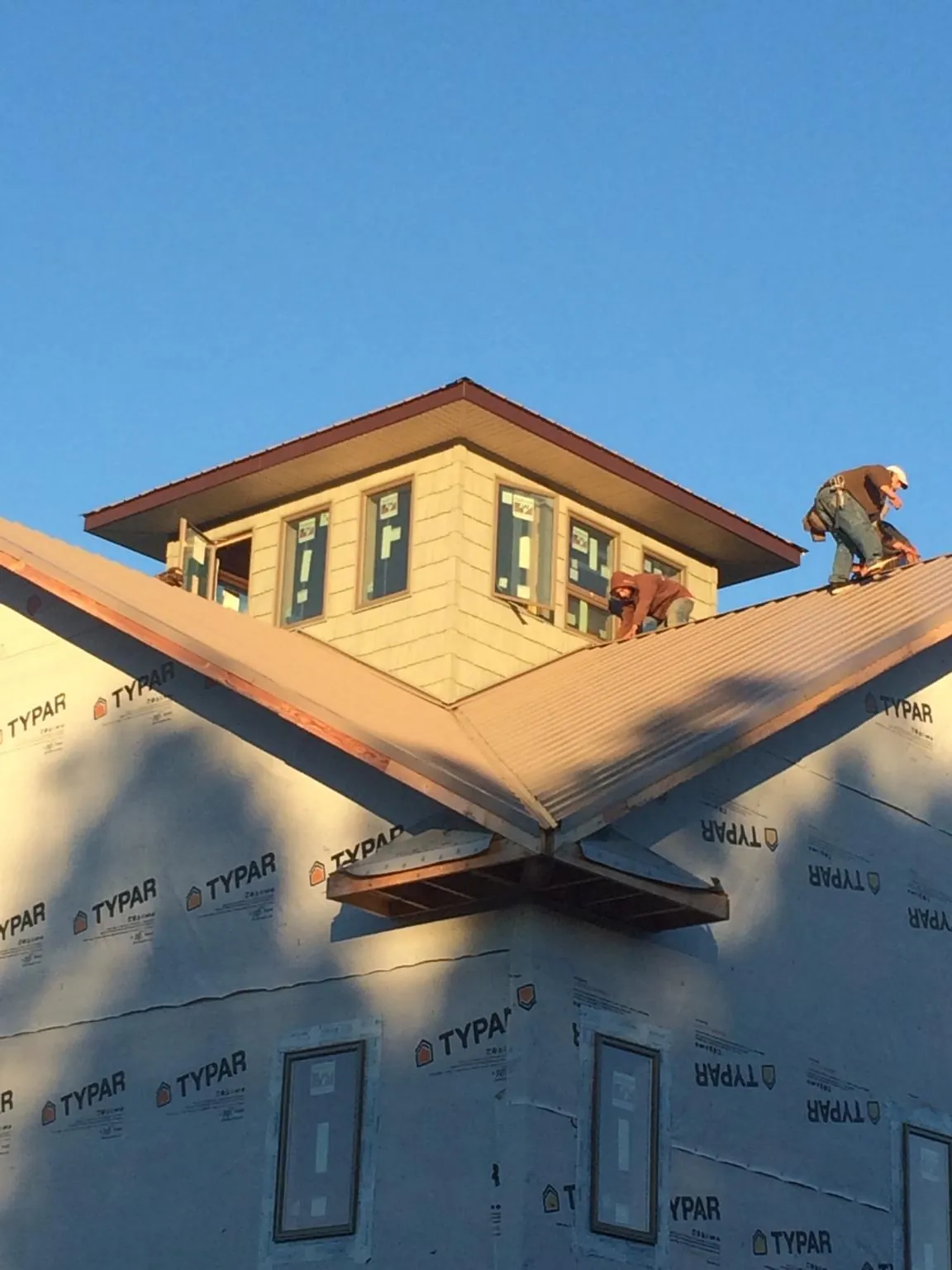 Roofers working around a rooftop cupola on a new metal roof at sunset — Roof Waterproofing in Silver Spring by Roofing Brothers